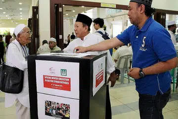 RINGANKAN PENDERITAAN: Jemaah di Masjid Muhajirin menghulurkan sumbangan mereka kepada tabung derma khas bagi menyediakan bantuan kepada pelarian Syria dalam menghadapi musim sejuk. - Foto MUIS