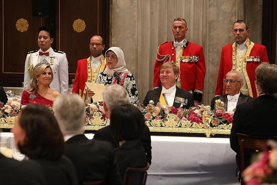 PERKUKUH IKATAN DUA NEGARA: Puan Halimah Yacob menarik perhatian mengenai hubungan ekonomi yang kukuh antara Singapura dengan Belanda semasa berucap di majlis jamuan negara di Istana Diraja Amsterdam. Turut dalam gambar ialah suami beliau, Encik Mohamed Abdullah Alhabshee (kanan, sedang duduk) serta Raja Willem-Alexander dan Ratu Maxima. - Foto MCI