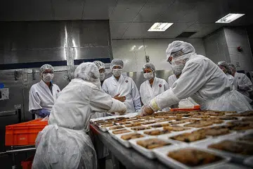 PERKHIDMATAN CEKAP: Encik Chee Hong Tat (menghadap kamera sambil memerhati pekerja) menyaksikan bagaimana kakitangan menyediakan makanan semasa lawatannya ke pusat katering dalam penerbangan SATS semalam, di mana beliau juga mengumumkan Program Bekerja dan Belajar (ELP) SkillsFuture baru untuk membantu pekerja sektor pengangkutan udara mempertingkat keupayaan mereka. - Foto BH oleh ARIFFIN JAMAR