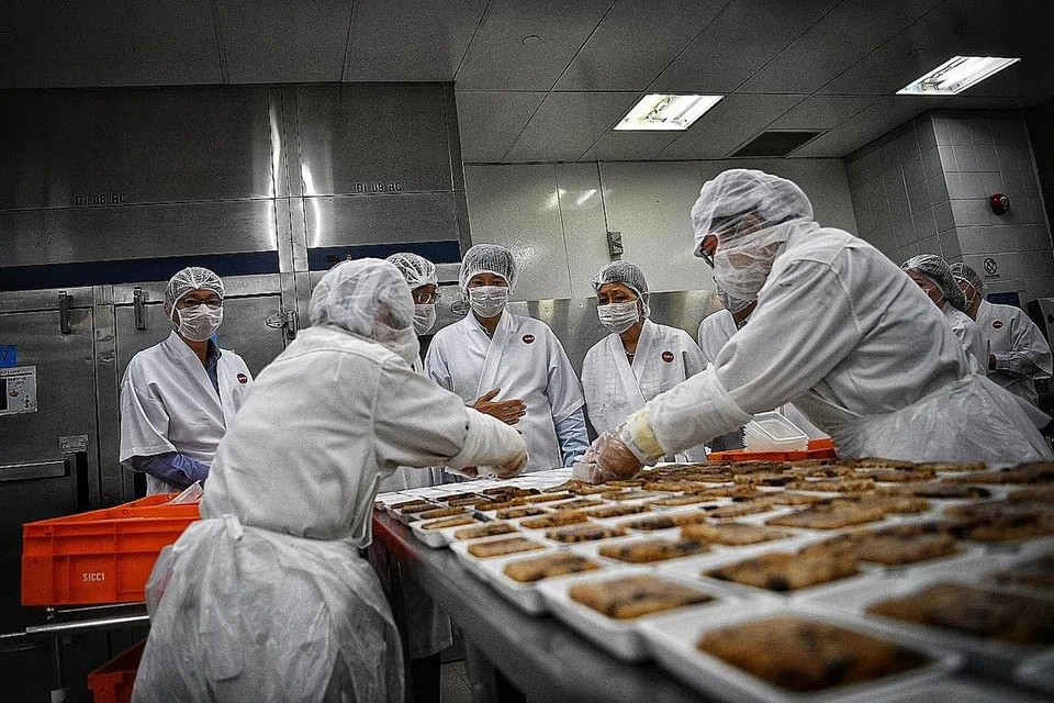 PERKHIDMATAN CEKAP: Encik Chee Hong Tat (menghadap kamera sambil memerhati pekerja) menyaksikan bagaimana kakitangan menyediakan makanan semasa lawatannya ke pusat katering dalam penerbangan SATS semalam, di mana beliau juga mengumumkan Program Bekerja dan Belajar (ELP) SkillsFuture baru untuk membantu pekerja sektor pengangkutan udara mempertingkat keupayaan mereka. - Foto BH oleh ARIFFIN JAMAR