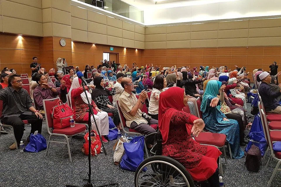 Riuh-rendah sekitar seminar - PELAJARI TEKNIK SENAMAN BERSAMA: Peserta yang menghidapi polio, Cik Aisah Ibrahim (berkerusi roda), bersama peserta seminar mempelajari teknik senaman yang boleh dilakukan ketika duduk sekalipun. Cik Aisah turut bertanya pelbagai soalan kepada panelis, misalnya perihal memakan makanan tambahan pada usia dan keadaannya. - Foto M.O. SALLEH