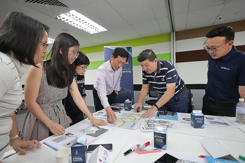 KEMAHIRAN DAN KECEKAPAN BARU: Menteri Pendidikan, Encik Ong Ye Kung (tiga dari kanan) dan Ketua Pegawai Eksekutif NTUC Learning Hub, Encik Kwek Kok Kwong berinteraksi bersama peserta dalam kelas pengekodan di NTUC Learning Hub semalam. - Foto BH oleh GAVIN FOO
