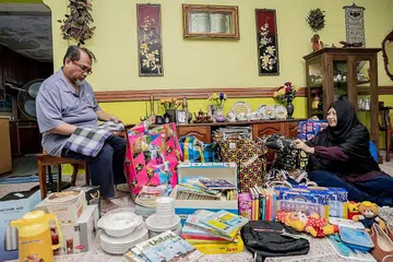 BANTU PEMBANTU RUMAH: Cik Lili (kanan) dan Encik Isro membelek-belek barangan terpakai yang diterima mereka melalui sumbangan masyarakat yang akan diagih-agihkan kepada golongan pembantu rumah serta keluarga mereka di kampung. - Foto BM oleh NUR DIYANA TAHA