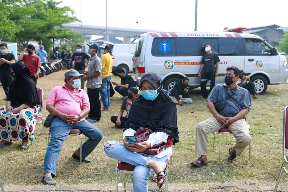 MENANTI GILIRAN: Orang ramai memakai pelitup sambil menunggu giliran untuk menjalani vaksinasi Covid-19 sedang kes terus melonjak di Jakarta, Indonesia, kelmarin. - Foto REUTERS