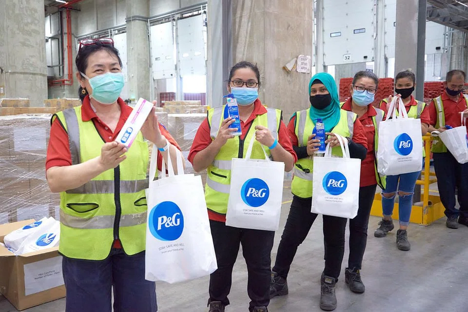 TANDA PENGHARGAAN: Pekerja gudang Redmart by Lazada bersama pek penjagaan Last Mile Heroes P&G yang mengandungi produk penjagaan peribadi. - Foto REDMART BY LAZADA