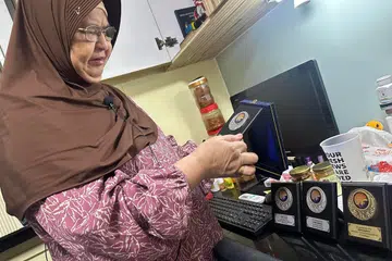 Cik Rahimah Lee Abdullah, 66 tahun, menunjukkan pingat sekolah Mohd Ridwan, yang telah lama disimpannya, sejak anak angkatnya itu meninggal dunia pada Julai 2021 dalam kemalangan di gelanggang bola keranjang di Bedok.