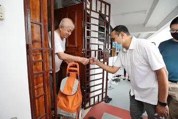 BANTU SESAMA JIRAN: Encik Zhulkarnain (kanan) turut serta dalam usaha mengagihkan pek keperluan harian kepada penduduk Keat Hong. - Foto PEJABAT DAERAH KEAT HONG