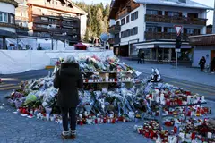 Seorang pengunjung berdiri di tapak di luar Bar Le Constellation di Crans-Montana, Switzerland, pada 4 Januari bagi memperingati mangsa yang terkorban. 