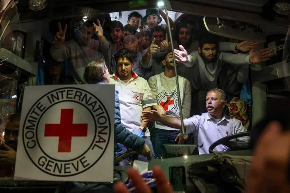 GERAKAN BANTUAN: Bas yang membawa anggota Pertubuhan Palang Merah Antarabangsa (ICRC) dan tahanan Palestin dipandu melepasi penyokong yang mengibarkan bendera Hamas di Ramallah sekitar Tebing Barat.