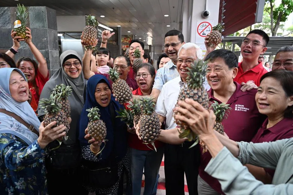 SENYUM LEBAR: Penyokong Encik Tharman masing-masing mendapat nanas dan meraikan kemenangan beliau.