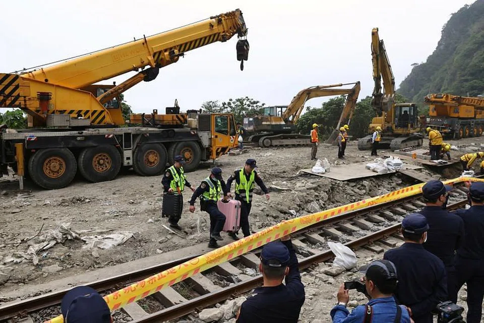 Para pegawai polis memindahkan barangan milik penumpang dari tapak kemalangan kereta api yang tergelincir di Hualien pada 3 April. 