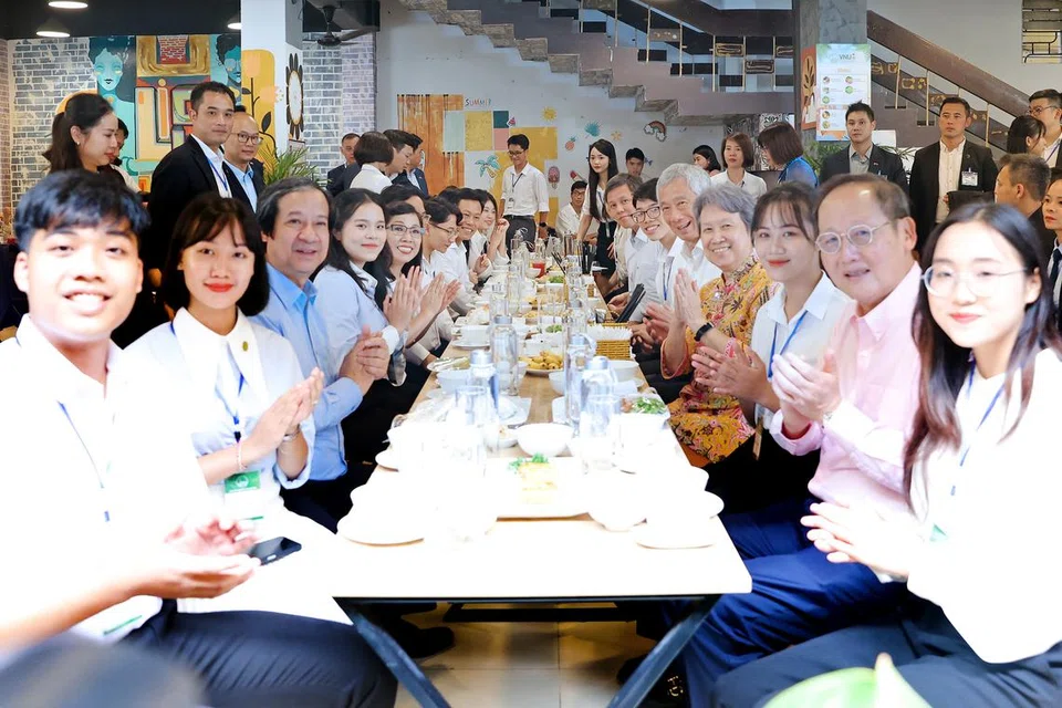 MAKAN BERSAMA PELAJAR: Perdana Menteri, Encik Lee Hsien Loong, dan isteri, Cik Ho Ching, (kanan, empat dan kanan dari depan), menikmati sajian tradisional Vietnam bersama pelajar di kantin kampus Universiti Nasional Vietnam, Hanoi (VNU). Turut serta ialah Menteri Tenaga Manusia, Dr Tan See Leng (kanan, dua dari depan), dan Menteri Pendidikan, Encik Chan Chun Sing (kanan, paling belakang). 
