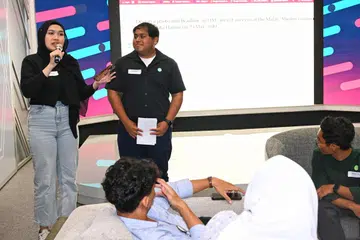 Encik Iskandar Zulkarnain (kanan) dan Cik Hannah Batrisyia Hamdi Hidayat, sedang membentangkan rumusan perbincangan kumpulan mereka mengenai bagaimana mereka merancang untuk terus belajar dan berkembang bagi mencapai cita-cita tersebut, serta peranan yang boleh dimainkan oleh masyarakat dalam menyokong perjalanan mereka.