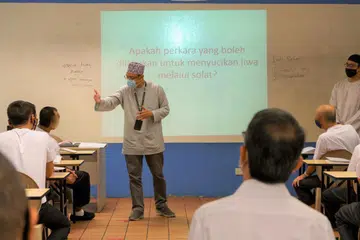 Ustaz Mohamed Effendi Suparde (kiri, berdiri) menganjurkan kelas pendidikan dan bimbingan agama kepada banduan.  