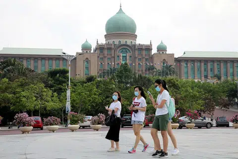PERANGI PENULARAN: Kerajaan Malaysia akan 'berperang' demi mengatasi penularan wabak koronavirus hingga tahun depan. Kelihatan sekumpulan pelancong melintasi depan Pejabat Perdana Menteri Malaysia di Putrajaya di peringkat awal Covid-19 melanda dunia lewat Januari lalu.