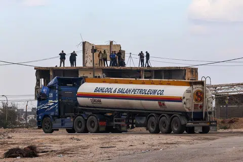 BEKALAN BAHAN API TIBA: Beberapa wartawan berdiri di atas bumbung bangunan untuk melaporkan ketibaan lori tangki yang membawa bahan api untuk dibawa ke Gaza menerusi Lintasan Rafah pada Rabu. 