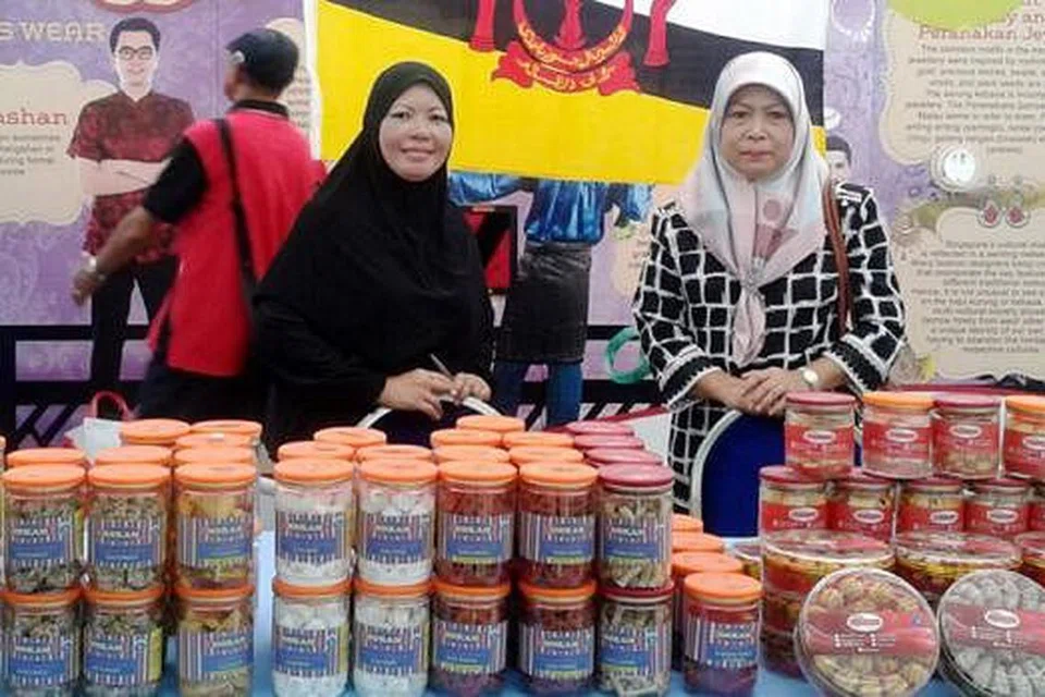 BERKONGSI BUDAYA BRUNEI: Hajjah Kamariah Hasbullah (kanan) bersama kakitangan syarikatnya menjual kuih-muih di gerai Brunei di bazar Ramadan Tampines untuk memberi pelanggan peluang menikmati rasa asli Brunei. - Foto ROZAIMEE ABDULLAH