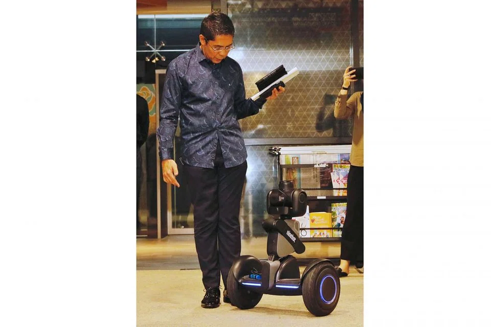 GUNA TEKNOLOGI CANGGIH: Dr Maliki (atas) mengamati ciri-ciri robot berautonomi yang sedang dalam peringkat percubaan sebelum ia digunakan untuk memenuhi keperluan pengawasan keselamatan bangunan WGS. - Foto BH oleh JEREMY KWAN