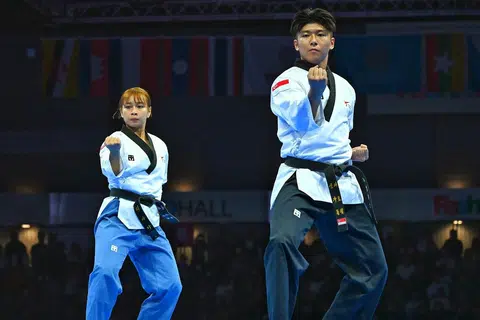 Diyanah (kiri) dan Nicholas Khaw (kanan) meraihkan pingat emas bagi acara regu campuran poomsae (seni), apabila menewaskan regu Vietnam di gelanggang Fashion Island Mall di Bangkok.