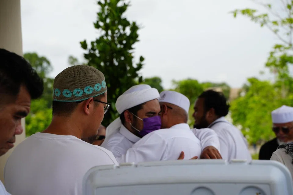 Anak kedua Allahyarham Ustaz Tengku Mohamad Fouzy Tengku Mahid Jumat, Ustaz Tengku Muhammad Fauwaz Jumat (tiga dari kiri), berpelukan selepas pengebumian Allahyarham di Pusara Aman sekitar 3.30 petang pada 19 Disember.