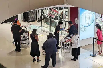 KEJADIAN TIDAK DIDUGA: Pegawai SCDF merawat seorang kakitangan kedai jenama Bobbi Brown setelah sebuah pintu panel kaca pecah, menyebabkan beliau mengalami luka di lengannya. - Foto BH oleh CHARMAINE NG