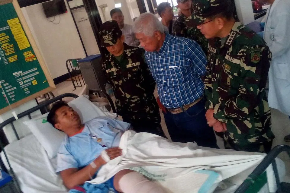 Setiausaha Pertahanan Filipina, Encik Voltaire Gazmin (dia dari kanan) dan Jeneral Hernando Iriberri (kanan) melawat salah seorang daripada 53 askar yang cedera di sebuah hospital tentera di Zamboanga di Mindanao pada Ahad (10 April), sehari selepas tentera bertempur dengan militan kumpulan Abu Sayyaf. 
