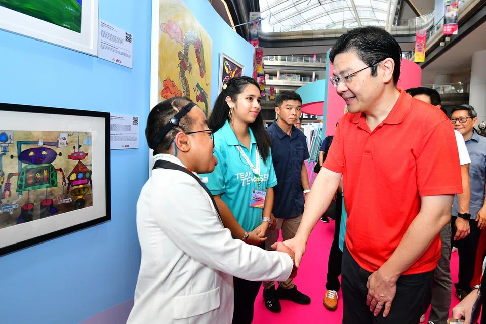 BERAMAH MESRA: Timbalan Perdana Menteri, Encik Lawrence Wong, berinteraksi dengan Encik Muhammed Ridhwan Masli, seorang artis dari Pusat Rainbow di pesta seni inklusif Shaping Hearts 2023 anjuran Majlis Pembangunan Masyarakat (CDC) North East di Our Tampines Hub pada Sabtu. Pusat Rainbow sebuah agensi khidmat sosial yang membantu memperkasa individu kurang upaya untuk berkembang maju dalam masyarakat inklusif.