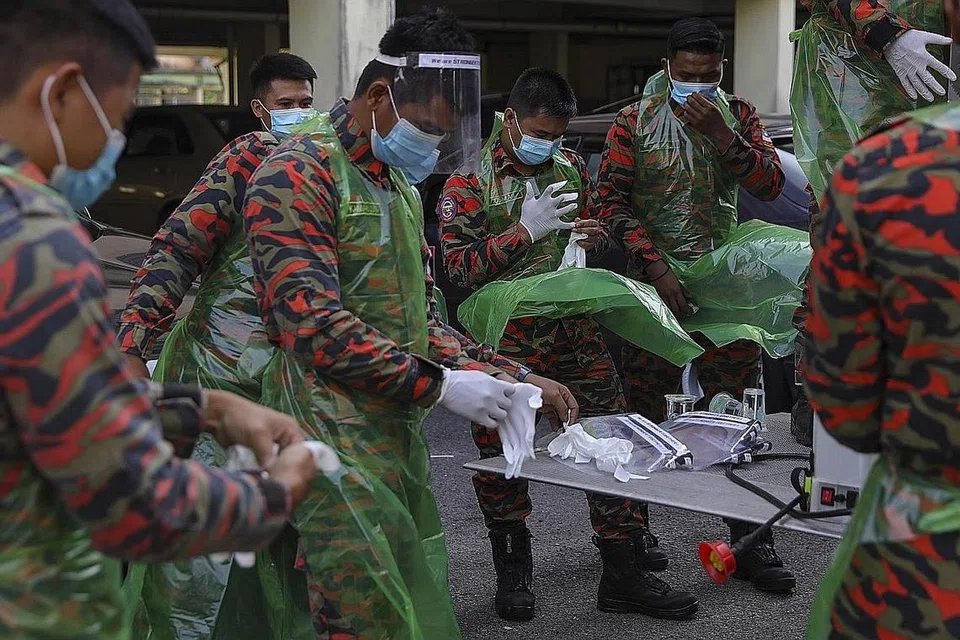 BERSIHKAN APARTMEN: Pasukan bomba Malaysia sedang bersiap sedia melakukan penyahjangkitan kuman di sebuah apartmen di Shah Alam, di luar Kuala Lumpur, berkaitan kes Covid-19. - Foto EPA-EFE