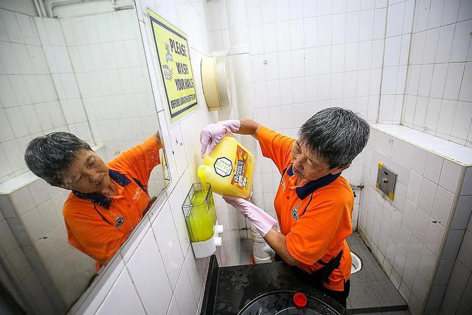 JAGA KEBERSIHAN: Seorang pekerja pembersihan sedang membersihkan tandas di sebuah kedai kopi di Yishun. Kajian di Singapura menunjukkan seorang pesakit Covid-19 boleh mencemari sekitarannya dan menjangkiti orang lain dengan cara itu. Justeru, permukaan dan peralatan yang kerap disentuh seperti mangkuk tandas perlu dibersihkan mengikut garis panduan yang ditetapkan. - Foto ZAOBAO