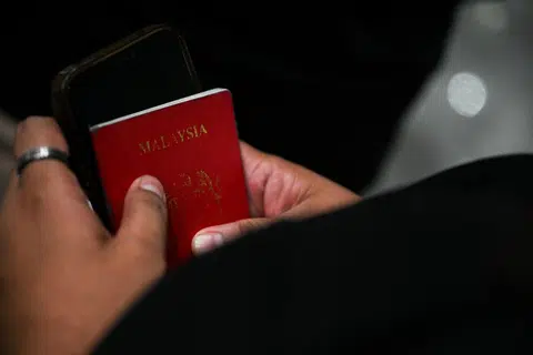 Cik Siti Nadzirah Mohd Khairi yang sedang memegang telefon dan pasportnya, sedang menunggu gilirannya di kelepasan kastam. 