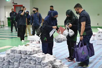 PENGAGIHAN: Sukarelawan di Masjid Assyakirin semalam mengumpul bungkusan daging korban dan paket nasi briyani untuk diagihkan kepada benefisiari Muis. - Foto BM oleh MOHD KHALID BABA