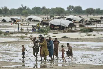 Penduduk membawa motosikal, berjalan melintasi tanah pertanian berikutan hujan susulan banjir monsun di Johi, daerah Dadu di wilayah Sindh, Pakistan pada 4 Ogos lalu. 