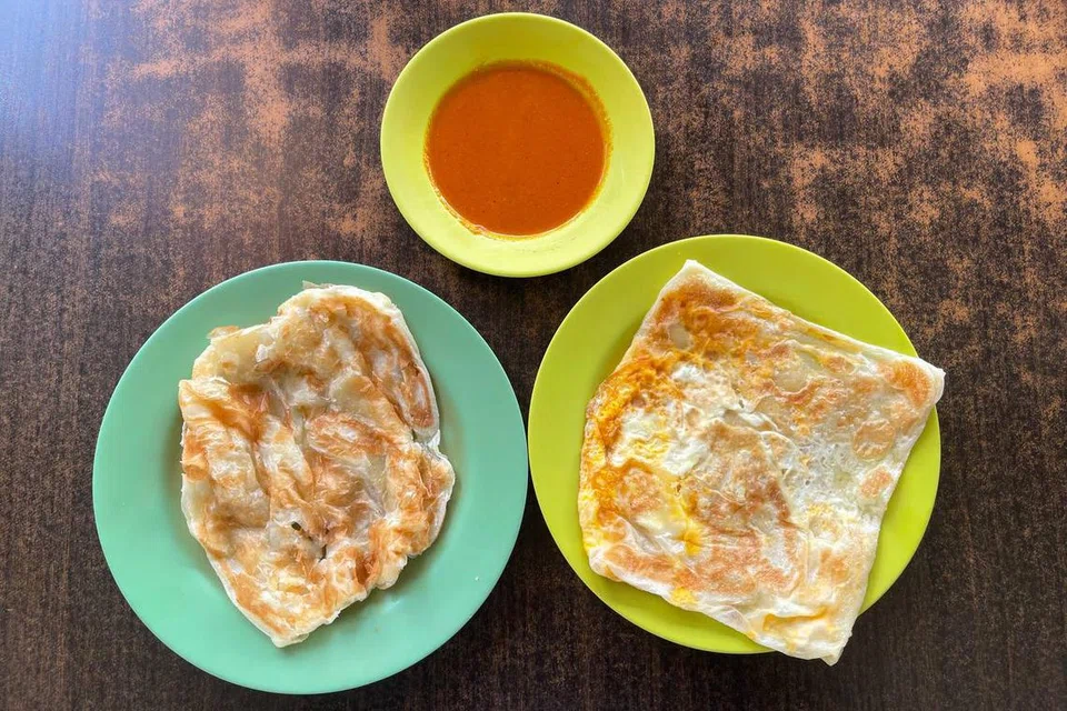 Roti perata kosong (kiri) dan roti perata telur (kanan) bersama kuah kari ikan yang masam dan pedas. 