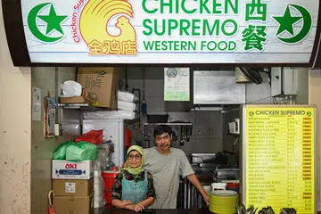 DIMINATI RAMAI: Pemilik gerai Chicken Supremo, Encik Soh Chin Soon (kanan) dan pekerjanya, Cik Zaleha Mohamed Petir (kiri), yang lebih dikenali sebagai ‘mak cik bismillah’, menjual hidangan makanan klasik Barat yang popular di Blok 493, Jurong West Street 41. 