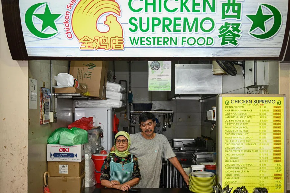 DIMINATI RAMAI: Pemilik gerai Chicken Supremo, Encik Soh Chin Soon (kanan) dan pekerjanya, Cik Zaleha Mohamed Petir (kiri), yang lebih dikenali sebagai ‘mak cik bismillah’, menjual hidangan makanan klasik Barat yang popular di Blok 493, Jurong West Street 41. 