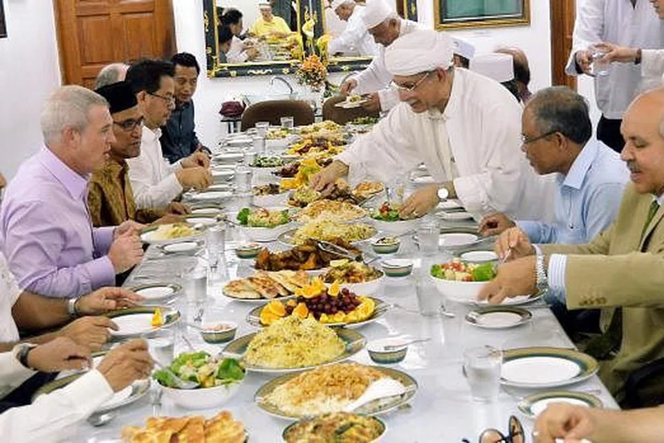 SEBELUM KE PARLIMEN: Encik Masagos (kanan) sempat menjamu selera bersaman beberapa kenalan dan jemaah termasuk (dua dari kanan) Habib Hassan, (dari kiri) Encik Kirk Wagar dan Encik Zainul Abidin. - Foto KHALID BABA