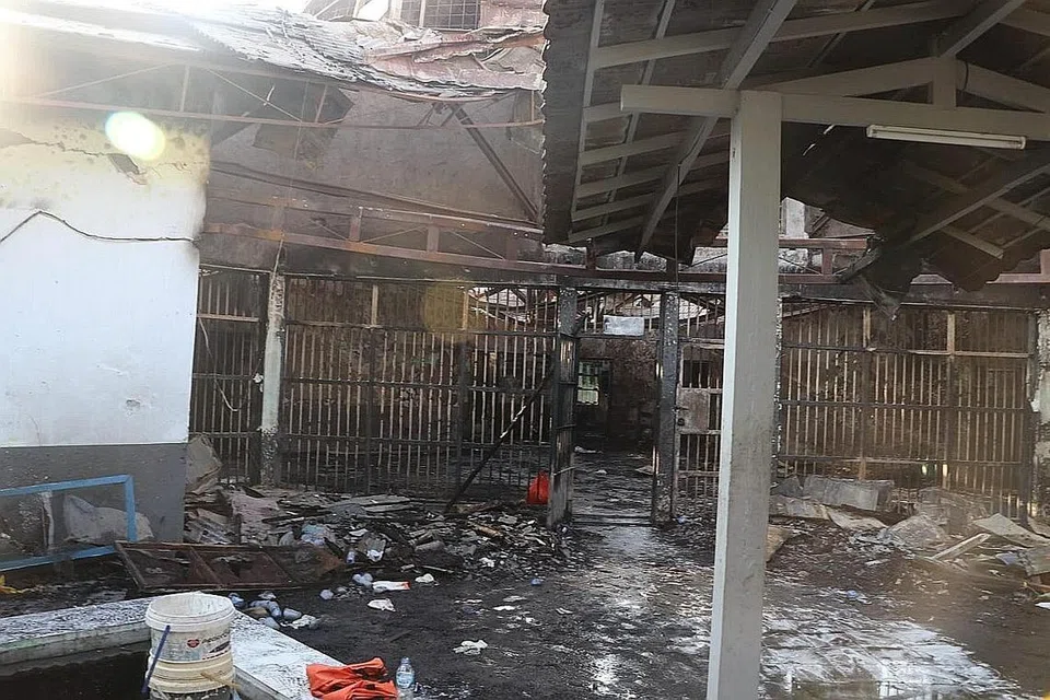 USAHA KENAL PASTI: Pekerja penjagaan kesihatan mengangkat beg mengandungi mayat seorang mangsa kebakaran penjara di Tangerang (gambar atas) bagi pengenalan identiti di sebuah hospital. - Foto REUTERS