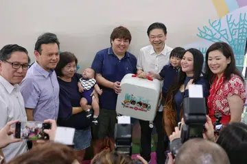 Perdana Menteri, Encik Lawrence Wong (empat dari kanan), menunjukkan Hadiah Bayi SG60. Bersamanya (dari kiri) Mayor Majlis Pembangunan Masyarakat (CDC) North West, Encik Alex Yam; Menteri Negara Kanan (Pertahanan merangkap Tenaga Manusia), Encik Zaqy Mohamad; dan Anggota Parlimen (AP) Kawasan Undi Perwakilan Berkumpulan (GRC) Marsiling-Yew Tee, Cik Hany Soh (kanan).