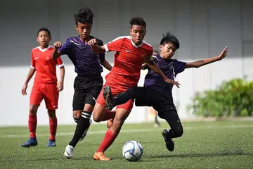 YANG MENGGELEK DAN MEMBENTES: Pemain SSP, Amir Syafiz (tengah) diasak dua pemain Queensway, namun ketangkasannya gagal dibendung Queensway dalam perlawanan akhir pertandingan NSG. SSP menjadi juara dengan kemenangan 2-1. - Foto SEKOLAH SUKAN SINGAPURA