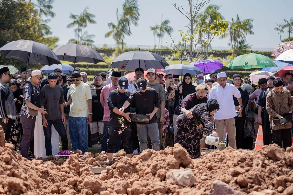 Ahli keluarga terdekat menaburkan bunga secara serentak di kubur (kiri) Allahyarham Mohammad Shahfiq Irman dan Allahyarham Mohamad Firman Nordin yang meninggal dunia dek satu nahas jalan raya di Johor. Pengebumian mereka telah dihadiri ratusan sanak saudara dan teman.