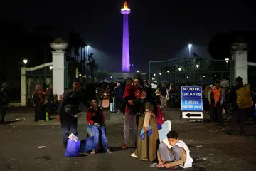 Penumpang bas menunggu di kawasan Monumen Nasional, Jakarta, Indonesia, pada 27 Mac sebelum menaiki kenderaan itu yang disediakan secara percuma oleh pemerintah Wilayah Jakarta untuk pulang ke kampung halaman, atau mudik, sempena Hari Raya Aidilfitri. 