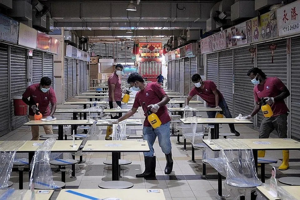 PUSAT PENJAJA DIBERSIH: Beberapa pekerja menjalankan kerja pembersihan dan pembasmian kuman di pusat penjaja makanan di tingkat satu Pusat Tekka yang ditutup. - Foto BH oleh GAVIN FOO