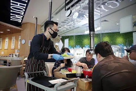ATUR CARA SELAMAT: Pelayan di restoran Jinshangyipin Buffet Hot Pot dilihat memakai sarung tangan, menyediakan makanan terlebih dahulu dan menyajikannya ke meja makan pelanggan. Restoran itu menerapkan khidmat bufet di meja sejak ia memulakan semula operasi pada 26 Jun lalu. - Foto BH oleh GIN TAY