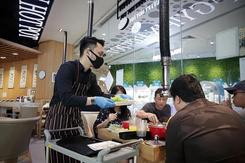 ATUR CARA SELAMAT: Pelayan di restoran Jinshangyipin Buffet Hot Pot dilihat memakai sarung tangan, menyediakan makanan terlebih dahulu dan menyajikannya ke meja makan pelanggan. Restoran itu menerapkan khidmat bufet di meja sejak ia memulakan semula operasi pada 26 Jun lalu. - Foto BH oleh GIN TAY
