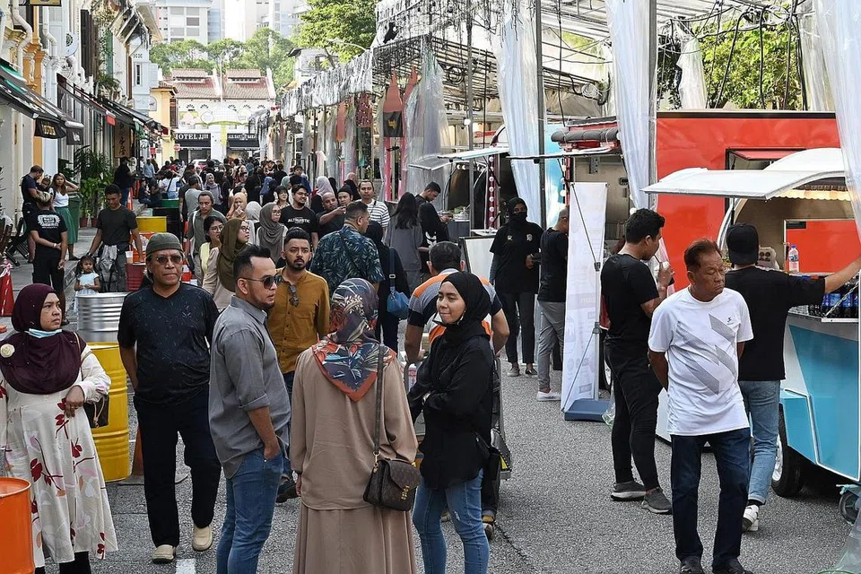 SUASANA MERIAH: Pengunjung di hari pertama bazar Raya di Kampong Glam. Gerai makanan di sepanjang Baghdad Street, Kandahar Street dan Sultan Gate akan menjula pelbagai makanan tradisional dan kuih raya. 