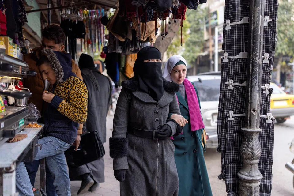 Sekumpulan wanita berjalan melalui Idlib, sebuah bandar di barat laut Syria yang ketika itu berada di bawah pentadbiran Hayat Tahrir al-Sham (HTS) pada 16 Disember.
