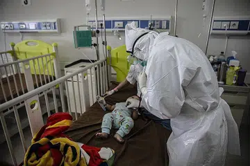 SI CILIK DIJANGKITI: Seorang doktor memeriksa seorang bayi yang diuji positif Covid-19 di sebuah hospital di Bogor pada 23 Jun lalu, sedang kadar jangkitan di Indonesia terus melonjak dan rumah sakit umum dibanjiri pesakit baharu, sekaligus memberi amaran akan krisis kesihatan yang mungkin berlaku hingga di luar kawalan di Indonesia. - Foto AFP