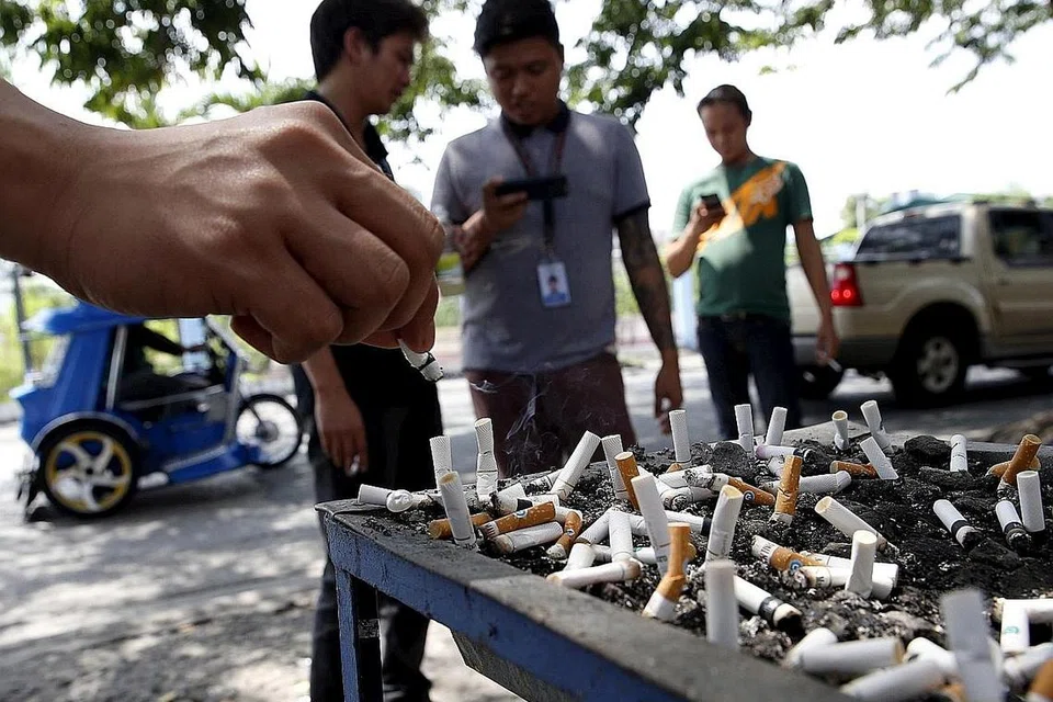 LARANGAN SEDANG DITIMBANG: Seorang perokok meletakkan puntung rokok di tempat membuang rokok dekat jalan raya di bandar Las Pinas, Manila, baru-baru ini, sedang pemerintah negara itu menimbangkan langkah melarang merokok di tempat awam. - Foto REUTERS