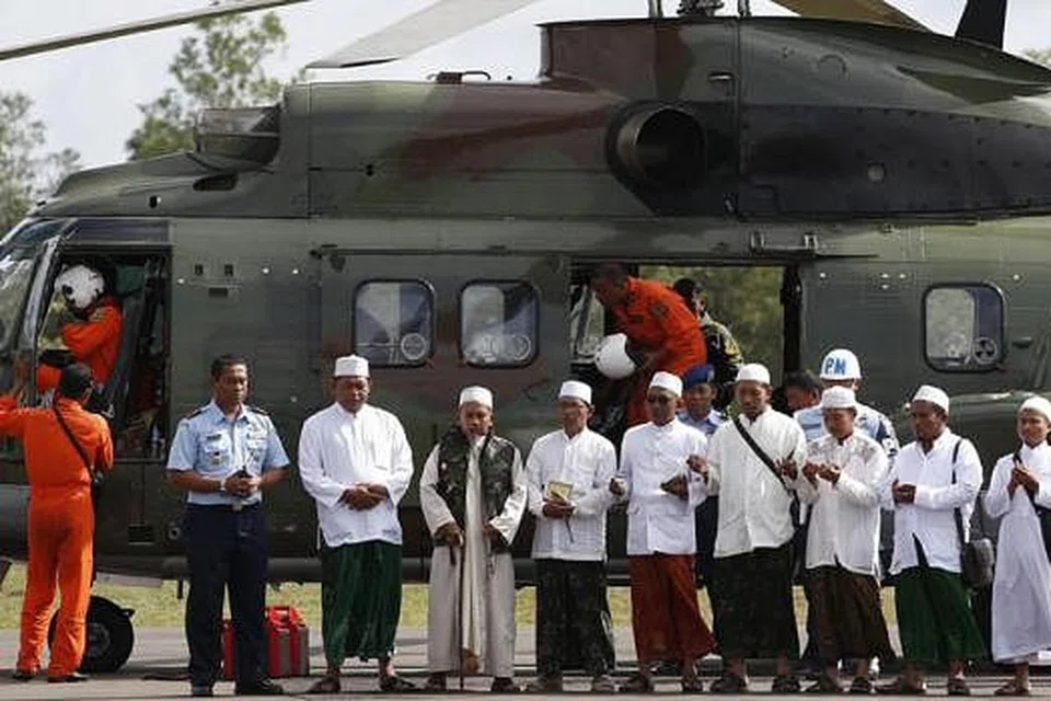 MEMANJATKAN DOA: Beberapa ustaz membacakan doa semasa menaiki helikopter tentera Indonesia di pangkalan tentera udara di Pangkalan Bun untuk ke tempat dipercayai lokasi nahas. - Foto REUTERS 