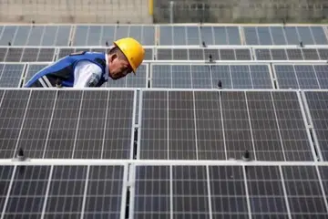 Seorang pekerja sedang memeriksa dan membersihkan panel-panel solar di stesen bas Jatijajar di Depok, Indonesia.